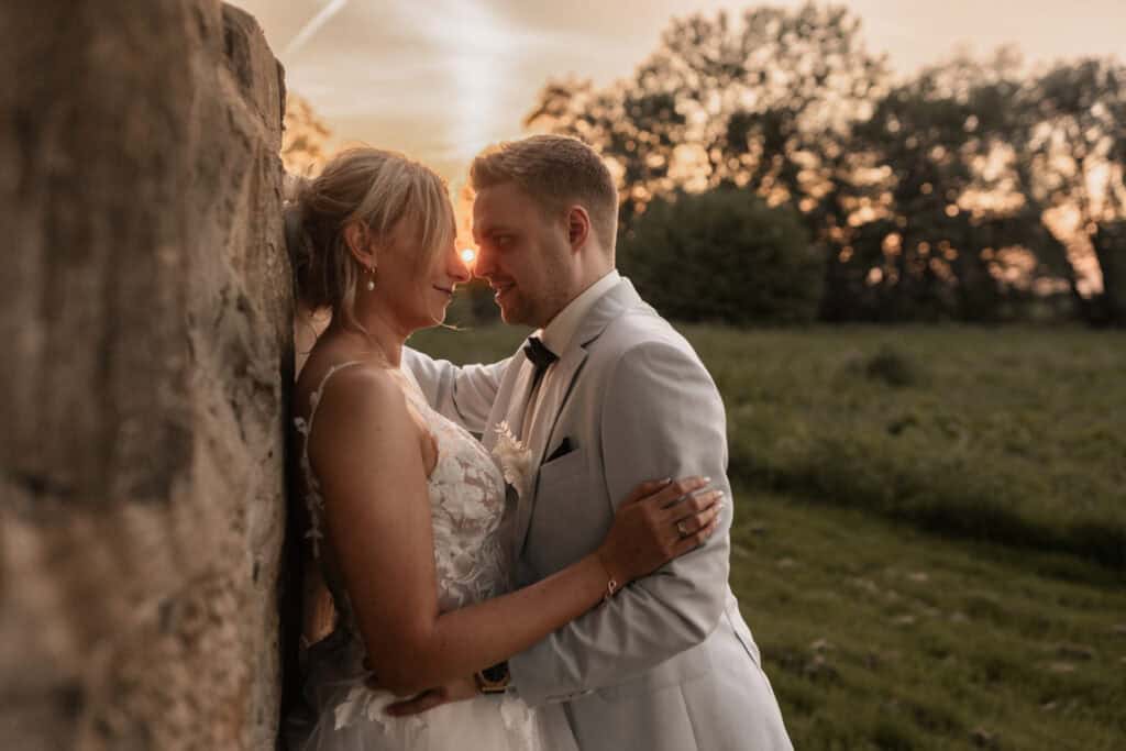 Braut und Bräutigam bei Sonnenuntergang im Grünen.