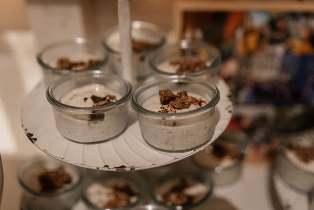 Dessert im Glas mit Schokoladenstückchen auf einer weißen Platte.
