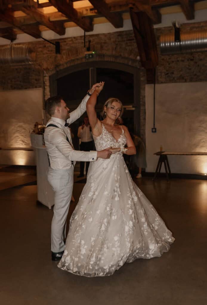 Braut und Bräutigam tanzen bei Hochzeit in rustikalem Ambiente.