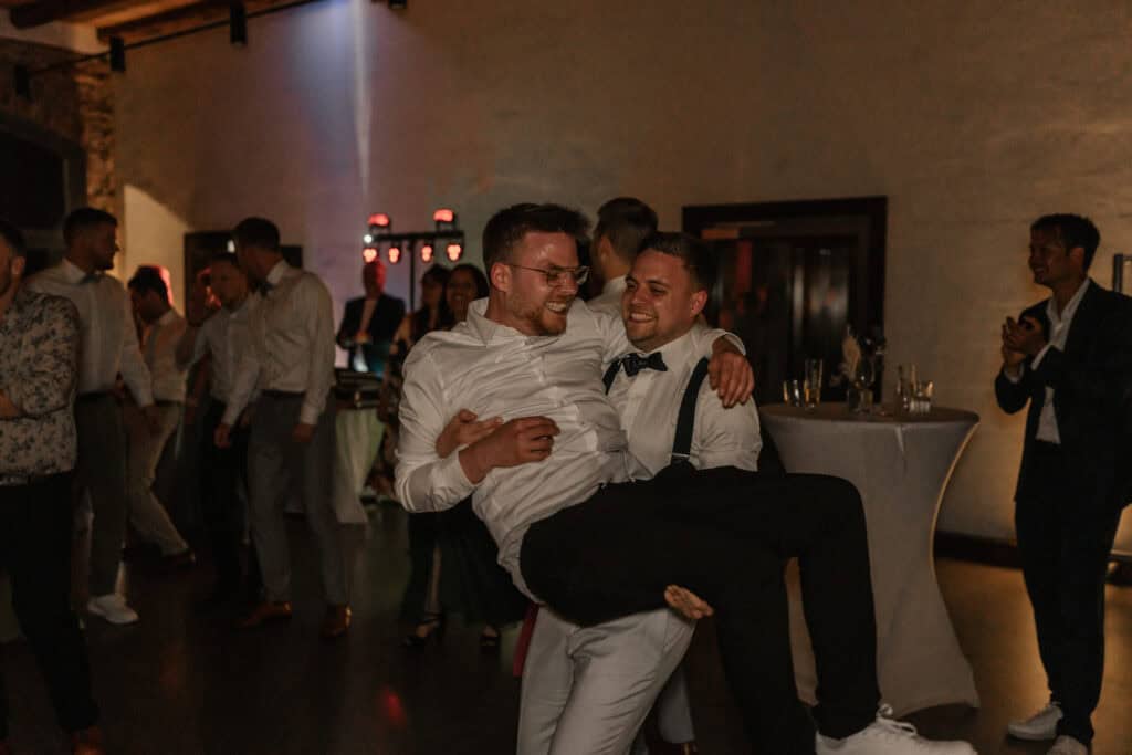 Junges Paar bei einer Hochzeit tanzt und lacht.