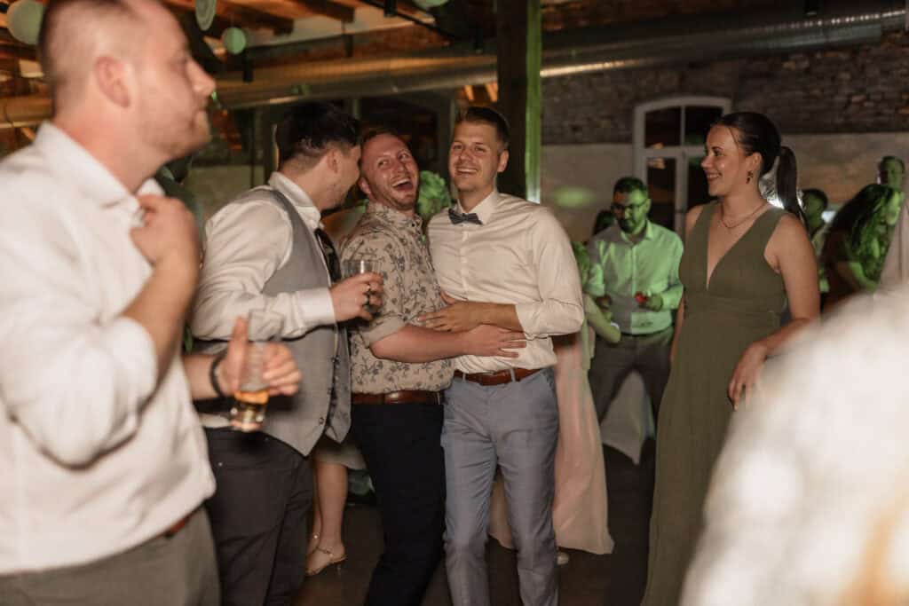 Freunde feiern auf einer Hochzeit im rustikalen Ambiente.