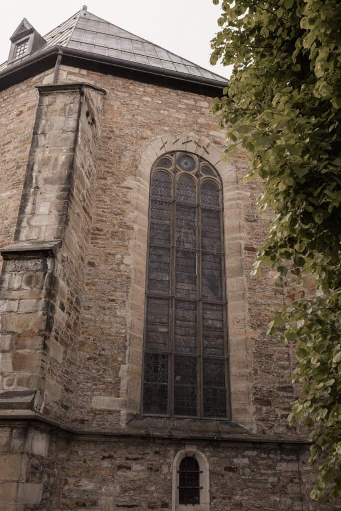 Historische Kirche mit großen gotischen Fenstern und Steinmauer.