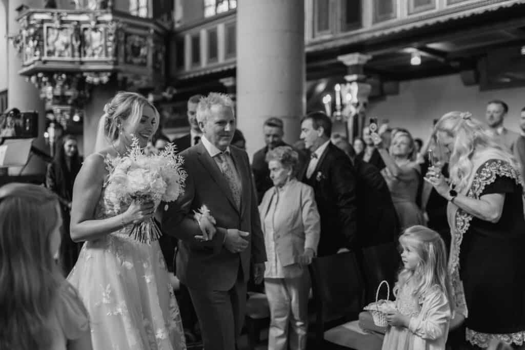 Hochzeitsszene mit Braut, Bräutigam und Gästen in Kirche.