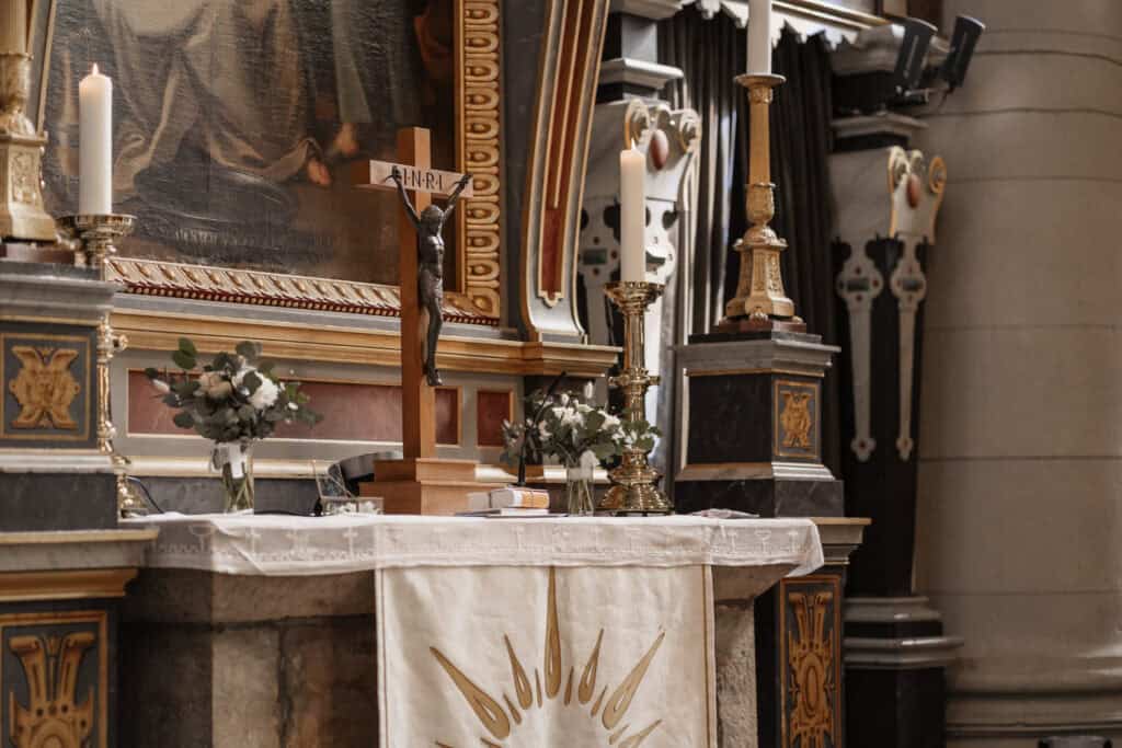 Altar mit Kerzen, Blumen und religiösen Symbolen in einer Kirche.