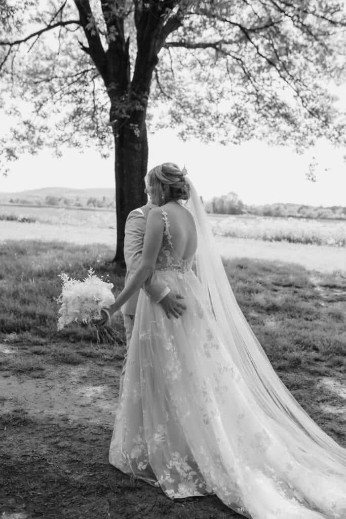 Braut in Hochzeitskleid mit Blumenstrauß im Freien bei Sonnenuntergang.