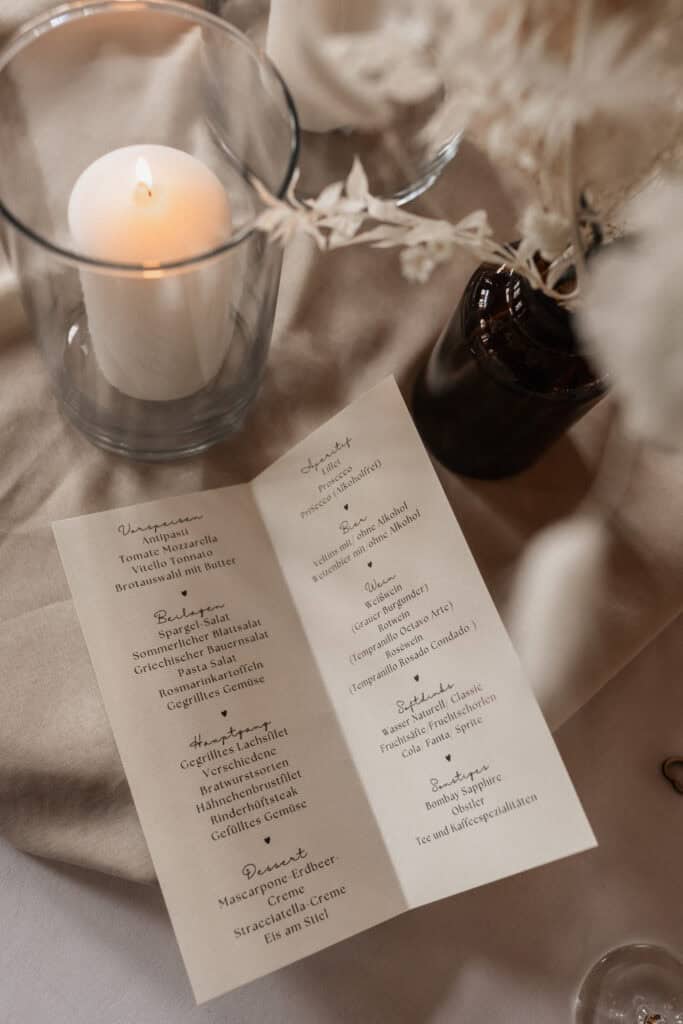 Hochzeitsmenü auf elegantem Tisch mit Kerze und Dekoration.