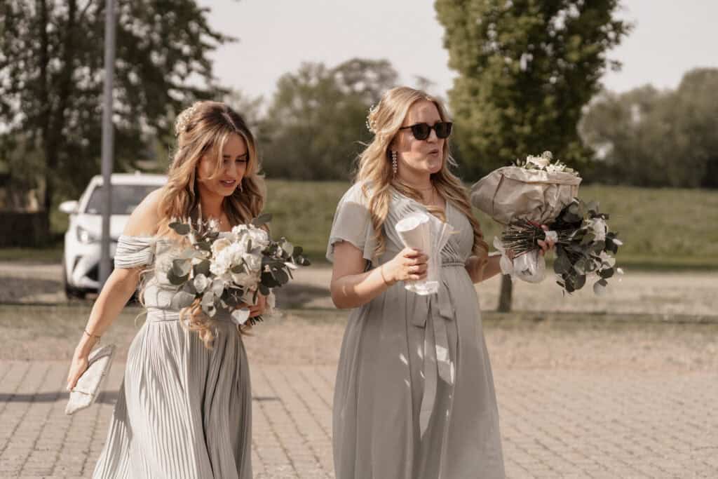 Zwei Frauen bei einer Hochzeitsfeier mit Blumen und Getränken im Freien.